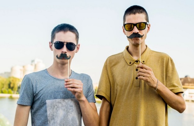 Two young men with fake moustaches. Movember for men's health.